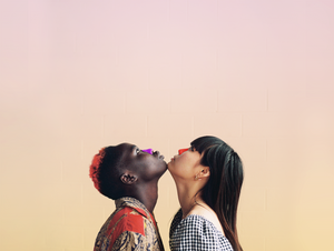 Two women with colorful sunscreen on their noses touching chins and looking up