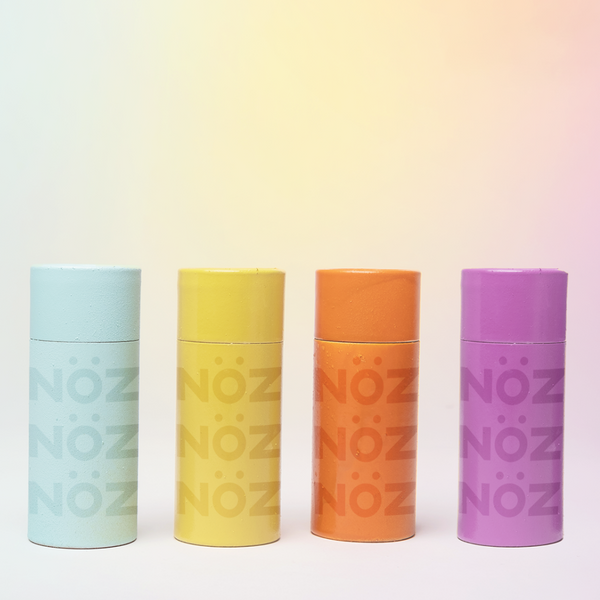 Four different colored small bottles of nose sunscreen in a straight line